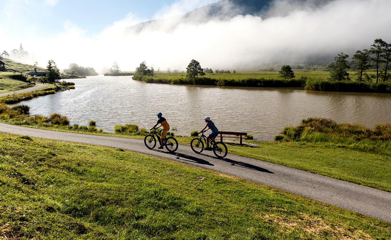 Zwei Radfahrer auf einem Pfad am Seeufer mit Nebel im Hintergrund © saalfelden-leogang.com Fotograf: Klemens König