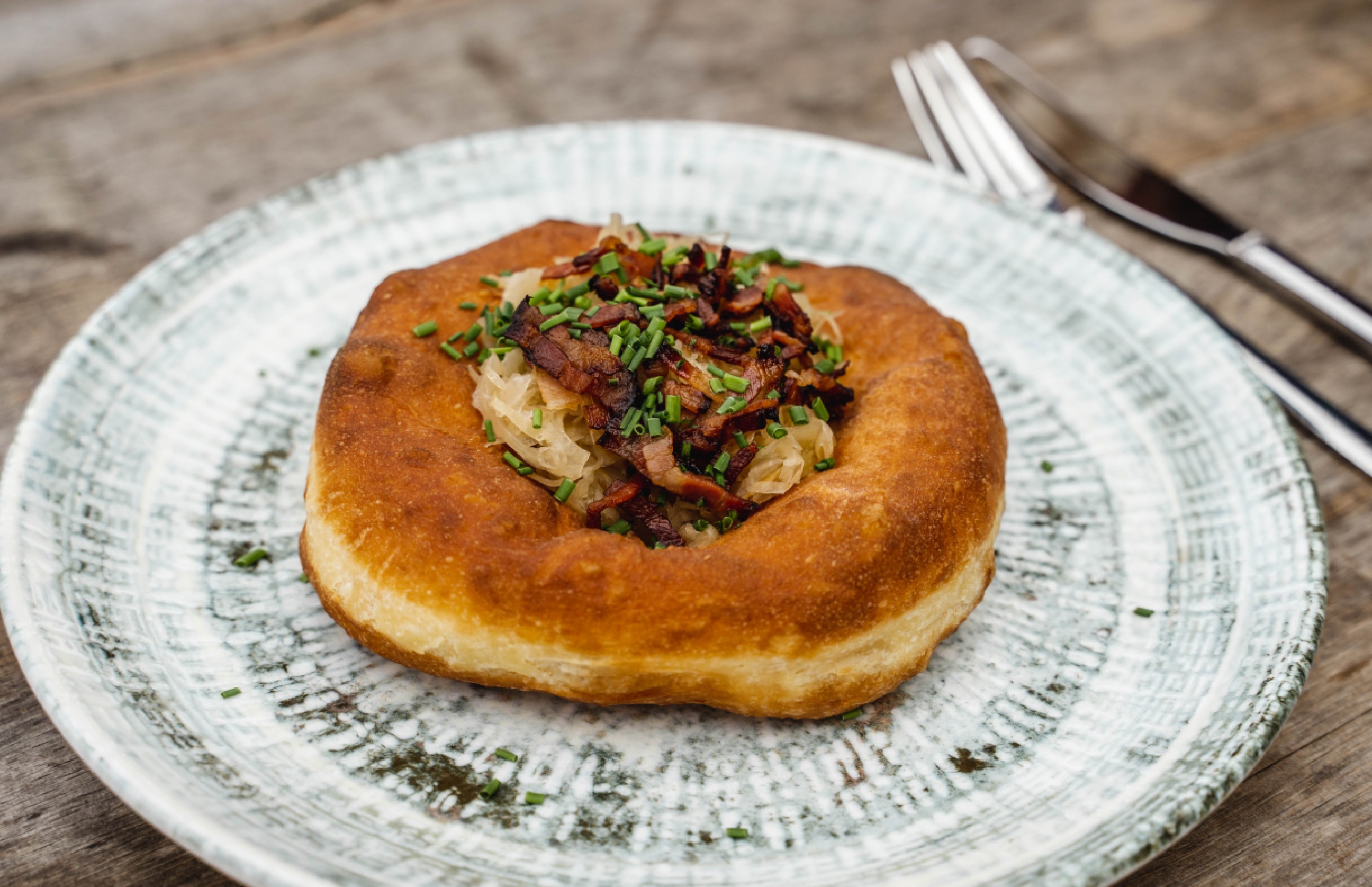 Frittierter Teigfladen gefüllt mit Sauerkraut und Speck auf einem Teller © Saalfelden Leogang Touristik / Fotograf: Michael Geißler