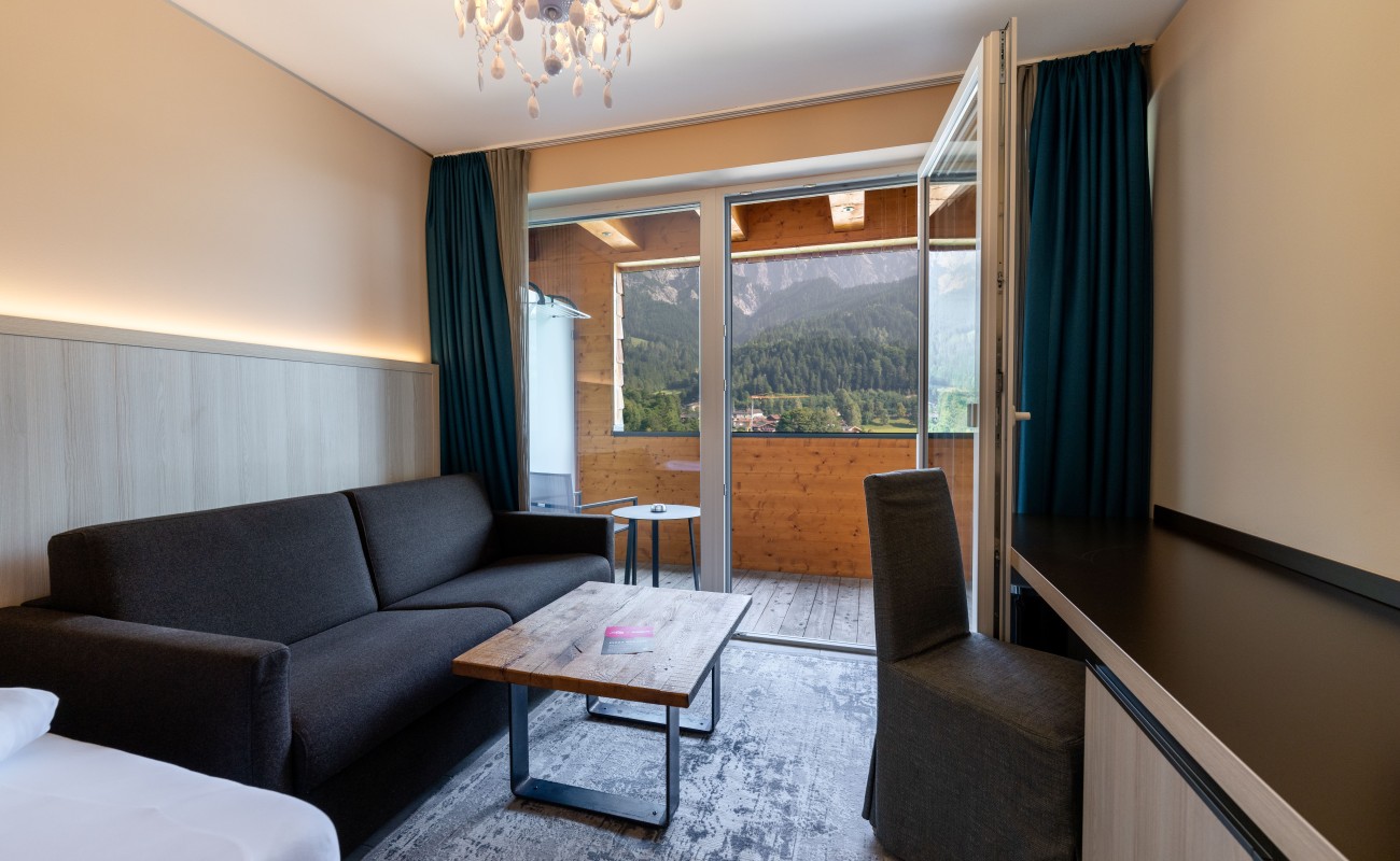Helles Schlafzimmer mit Kronleuchter über einem Bett und Holzmöbeln